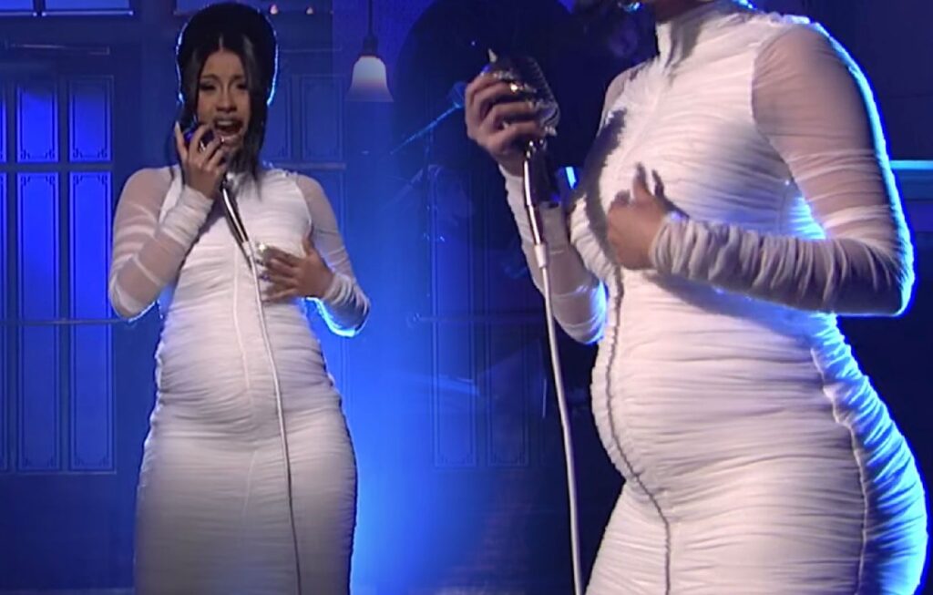 Photo of Cardi B performing while pregnant in a white dress.