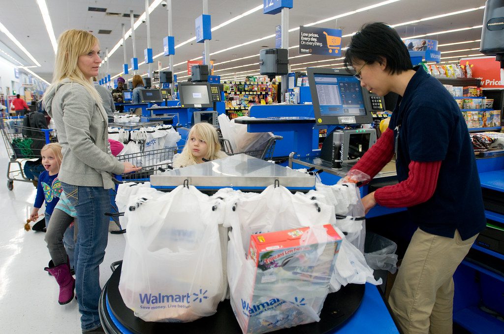 woman checking out groceries with her children.