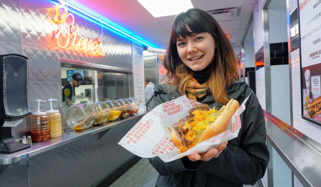photo of woman holding one of Steve's  Philly cheesesteaks,