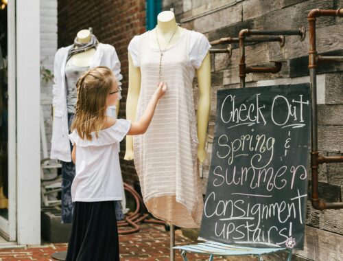 Young woman standing outside a consignment store, highlighting sustainable fashion and secondhand shopping.